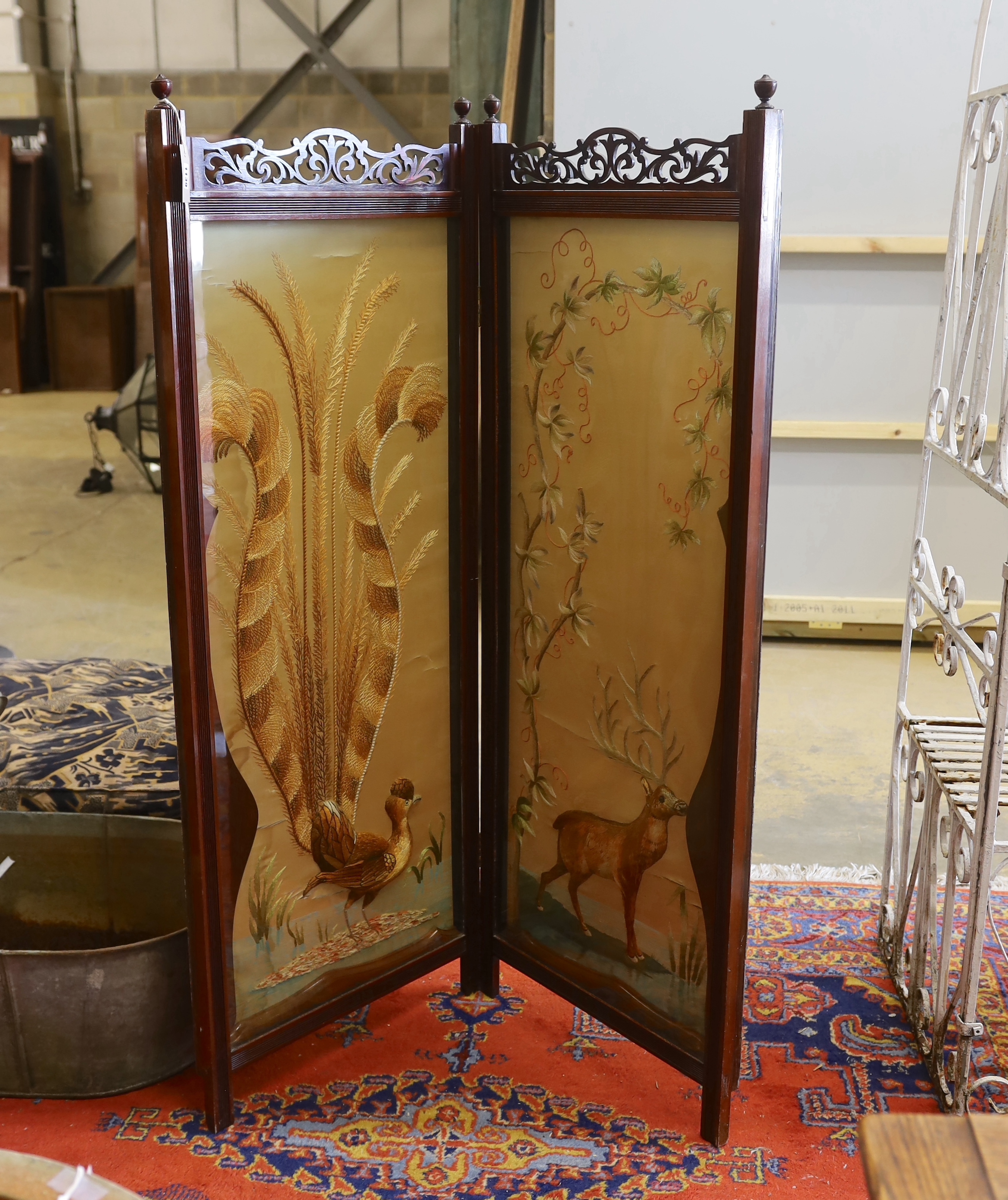 An Edwardian silk thread embroidered two fold dressing screen worked with a peacock and a stag, each panel width 57cm, height 152cm